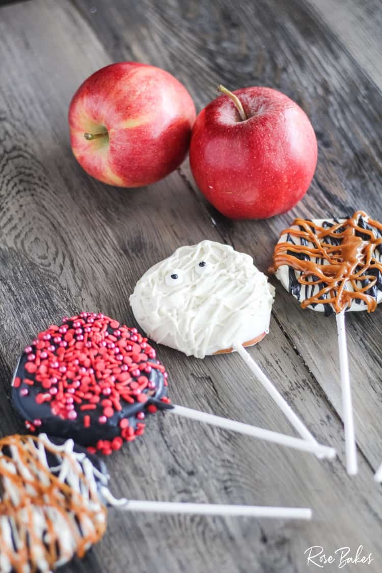 Chocolate dipped apple pops displayed with a couple of whole apples