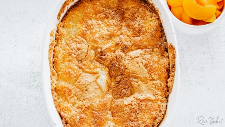 baked peach cobbler in an oval white casserole dish