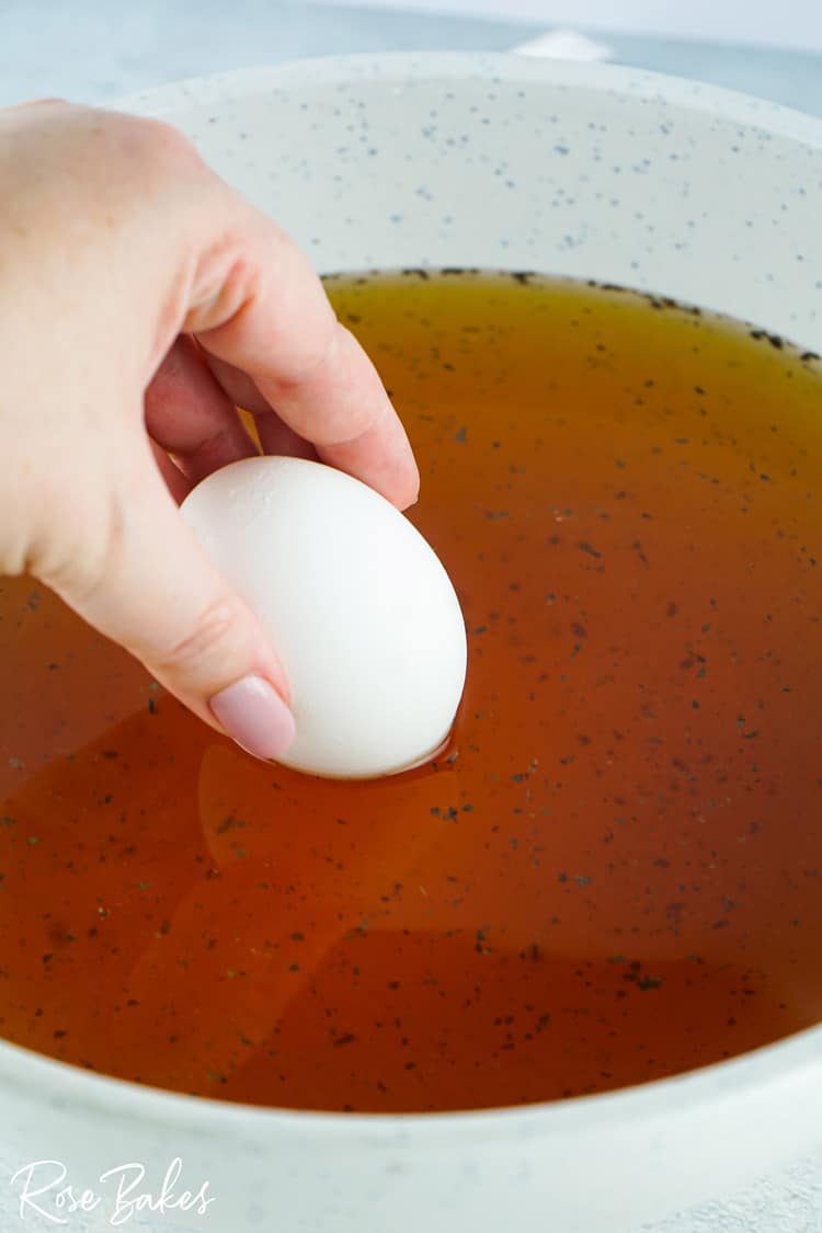 eggs being placed in tea and vinegar mixture 