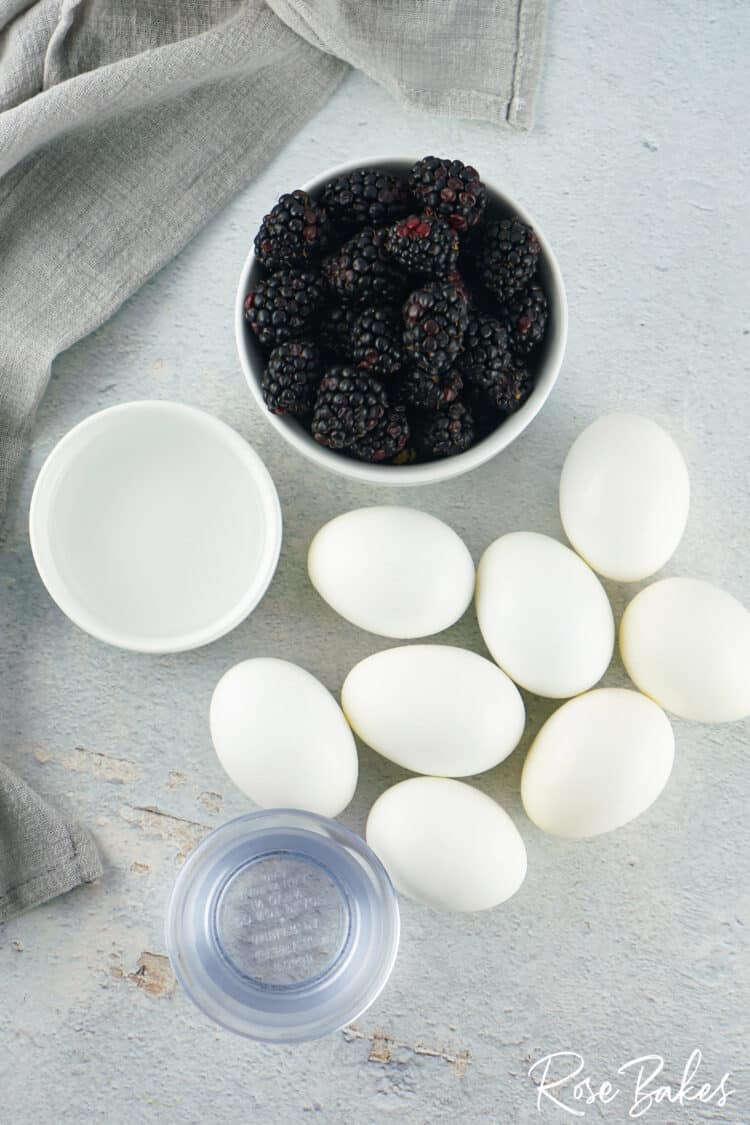 bowl of blackberries and white eggs spaced around 