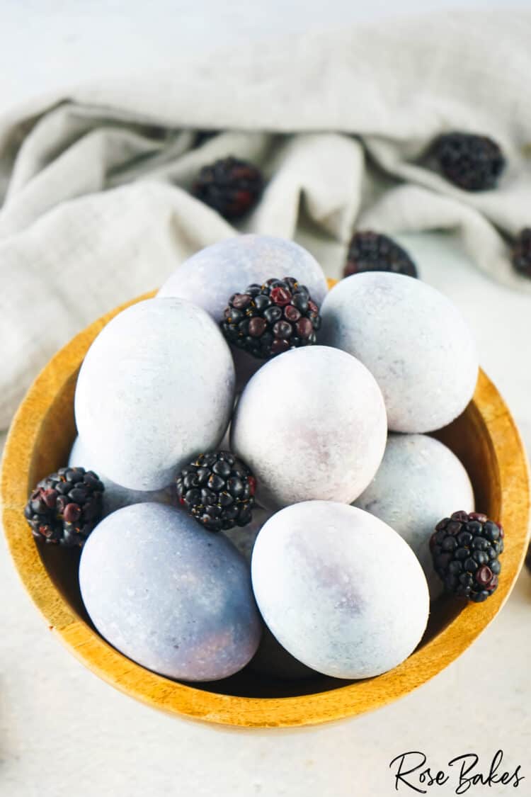 dyed eggs in wooden bowl with fresh black berries 