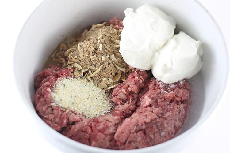 Raw meat and ingredients in bowl for burgers