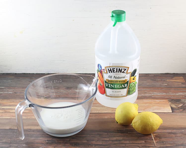 cup of milk with lemons and white vinegar bottle