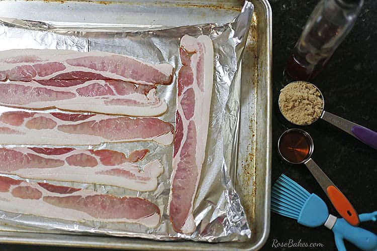 baking sheet lined with foil and raw slices of bacon on the foil.