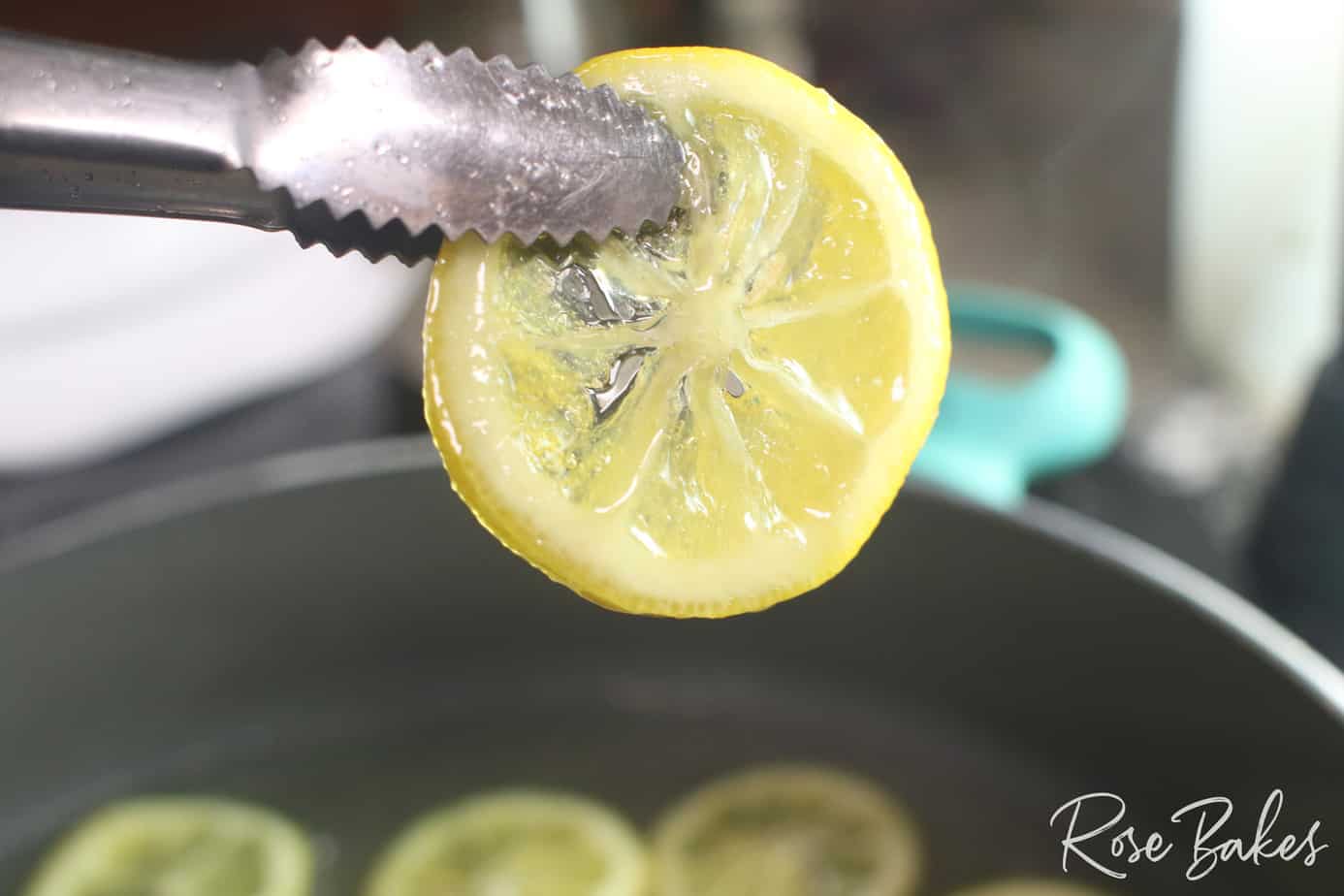 tongs holding lemon slices in a shallow pan of sugar water that is boiling