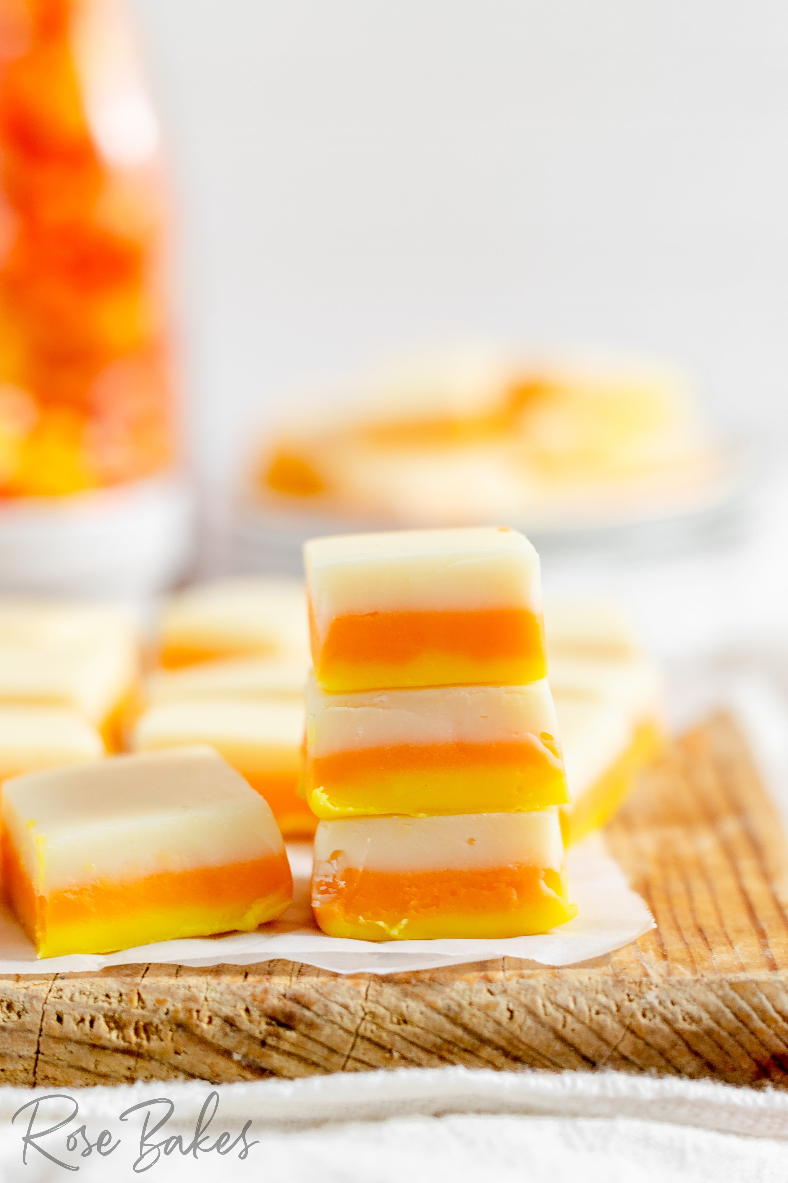 stack of squares of candy corn fudge on a wooden cutting board
