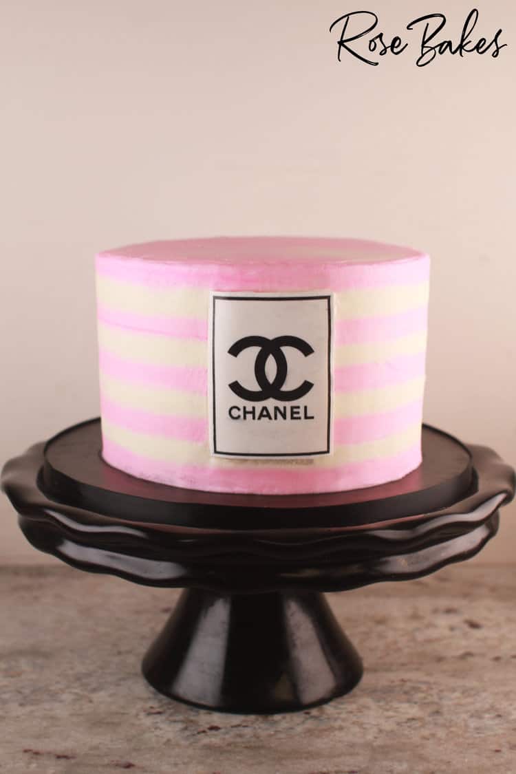 Pink and white buttercream striped cake with a Chanel logo on the front of the cake.