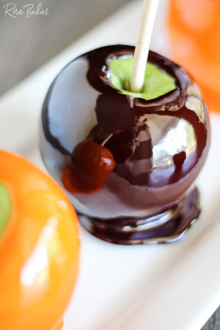 Close up of a black candy apple with reflection of an orange candy apple in the shiny candy.