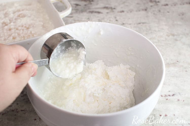 white mixing bowl with cool whip and coconut syrup