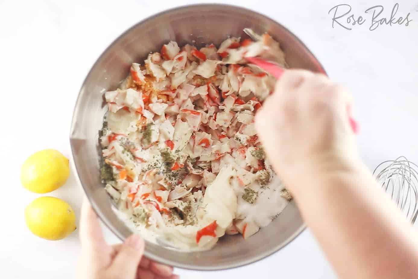 mixing Creamy Crab Pasta Salad ingredients in a silver bowl