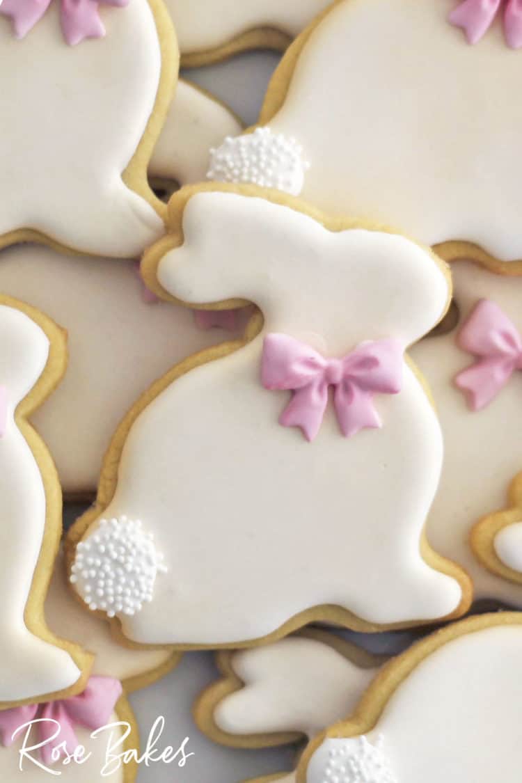 A close-up of a decorated Easter Bunny Cookie with a pink bow and nonpareil poofy tail
