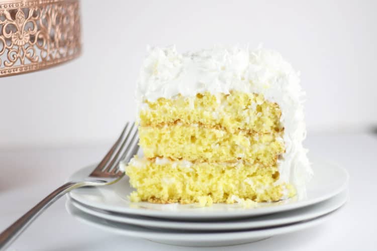 slice of coconut cake on white plate with fork