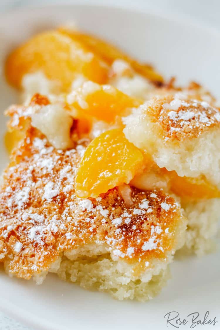 Close up of Easy Peach Cobbler on a white dish with powdered sugar dusted over the top.