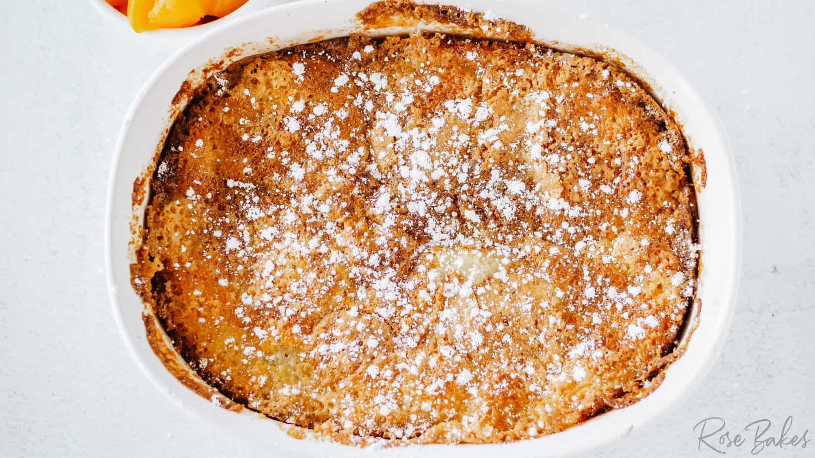 baked easy peach cobbler in an oval white casserole dish