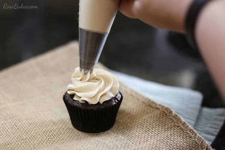 Chocolate cupcake with maple brown sugar buttercream being piped onto it.