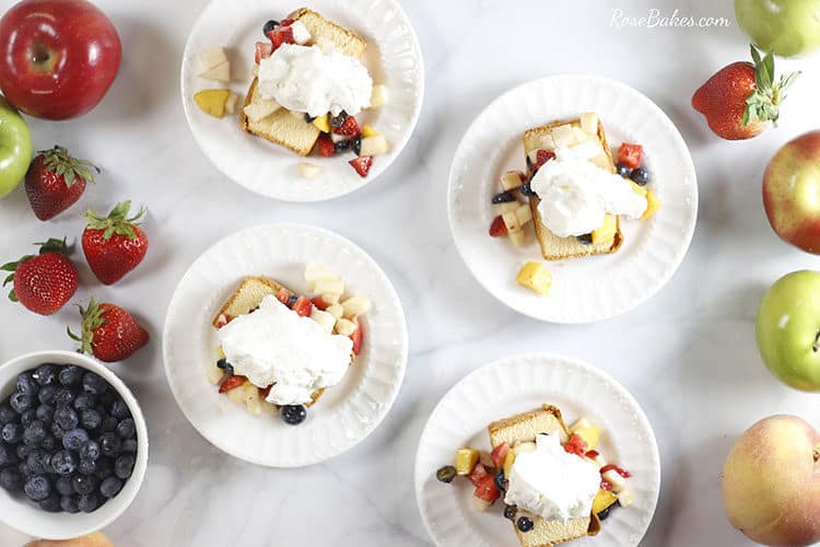 4 dessert plates with slices of pound cake each topped with fruit salsa and whipped cream.