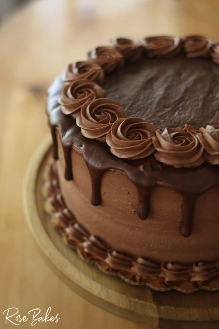 A close up view of the chocolate drip and rosettes on the finished, decorated cake.