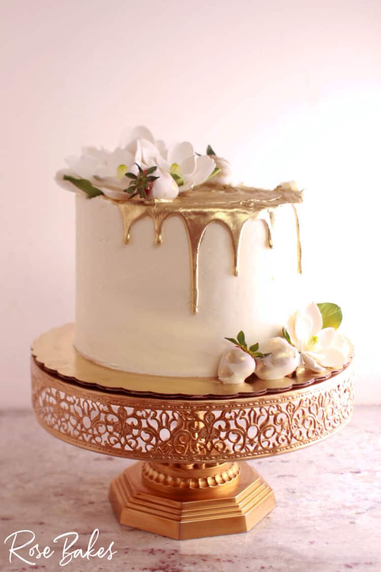 one tier Gold Drip Cake with Sugar Magnolias & Strawberries on gold cake stand
