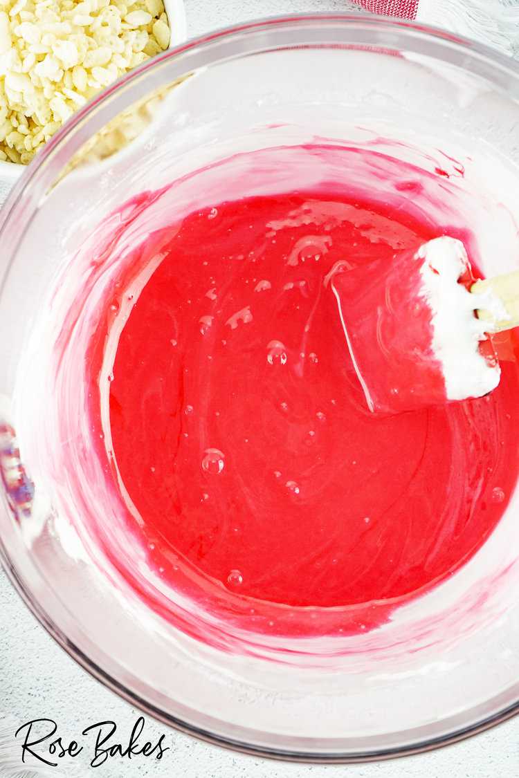 melted butter and marshmallows in a clear bowl with red coloring mixed in