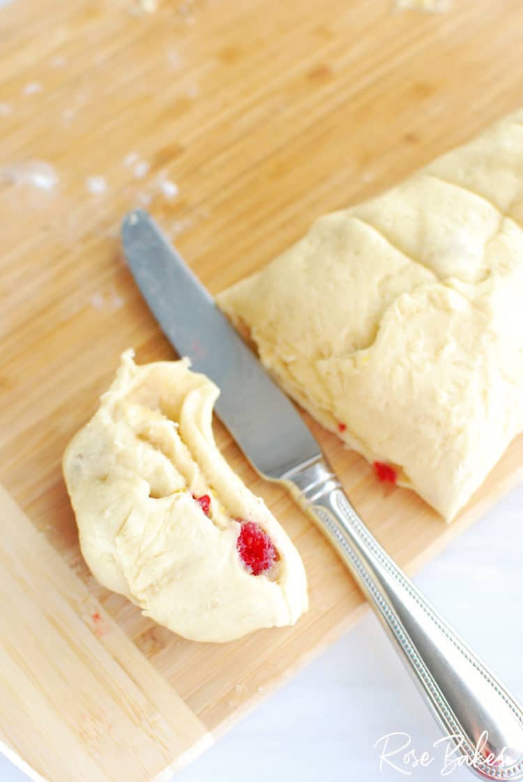 Raspberry Cinnamon Rolls dough rolled out on cutting board rolled up and ready for cutting