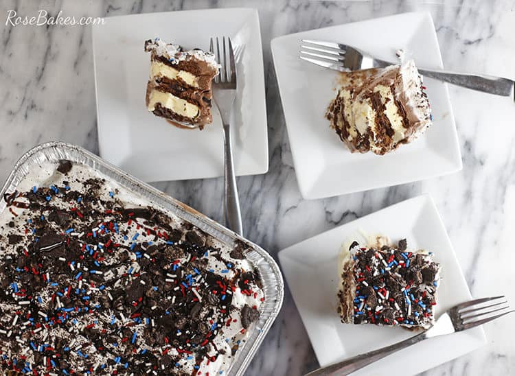Pan of ice cream sandwich cake with 3 slices plated on white square plates and silver forks on each plate.