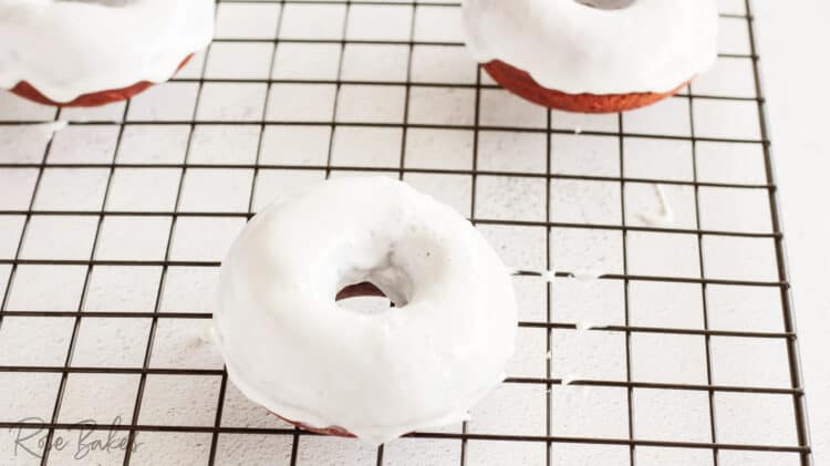 red velvet donuts dipped in frosting on a cooling rack