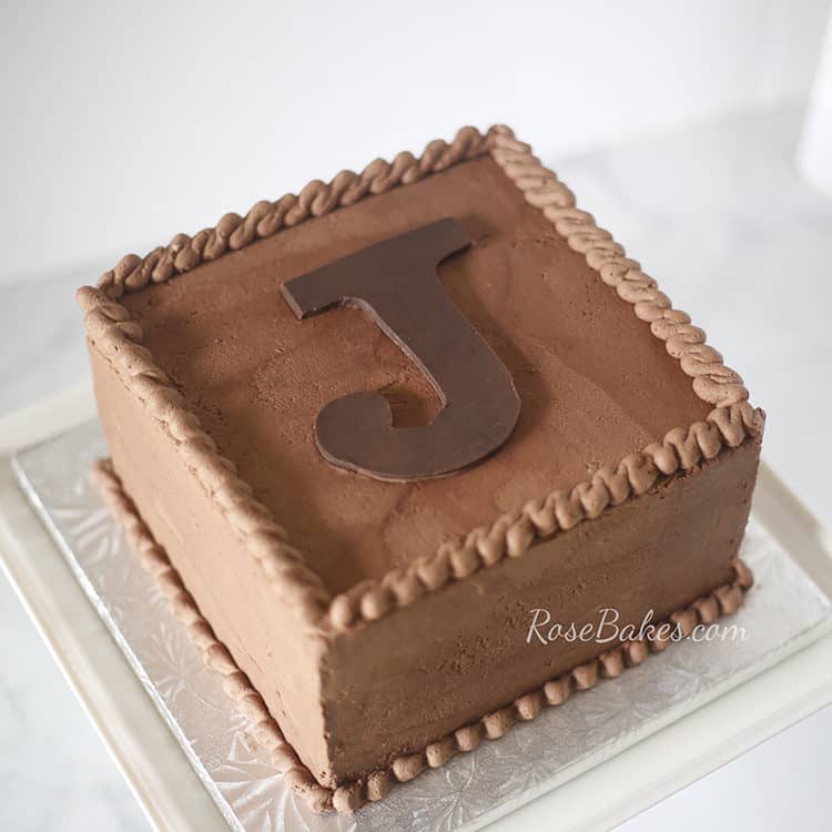 square chocolate cake with large initial cut out as topper