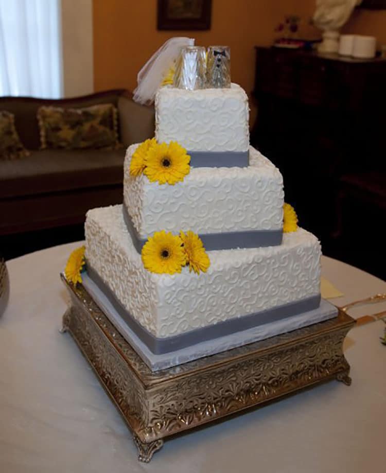 White Wedding Cake with Gray Ribbon and Yellow Gerber Daisies
