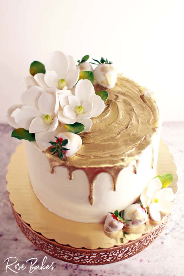 Gold drip cake with sugar magnolias and strawberries 