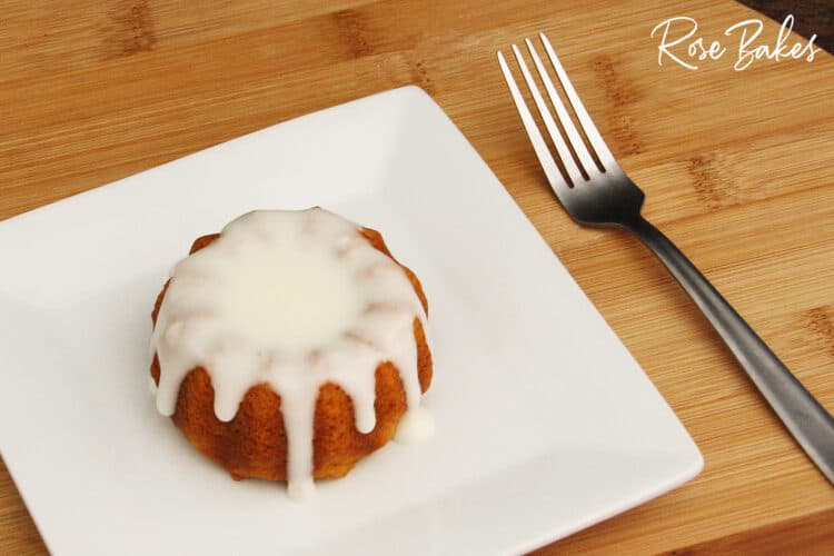 a single mini pumpkin spice bundt cake with cream cheese glaze on white square plate