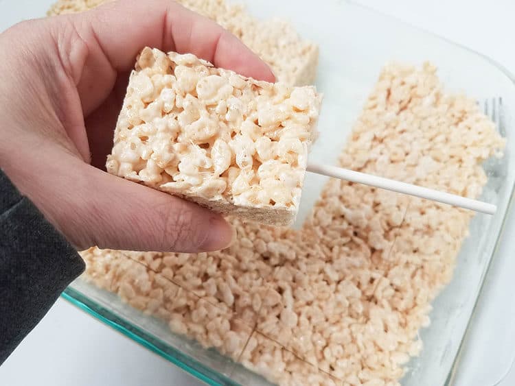 pushing a lollipop stick into rice krispies treat for Easter Rice Krispies Pops
