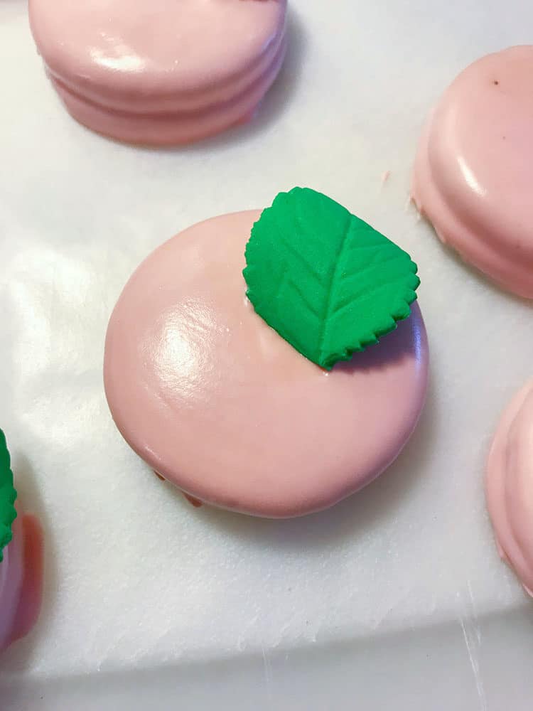 oreo dipped in pink candy melts with green leaf for easy oreo flower cookies