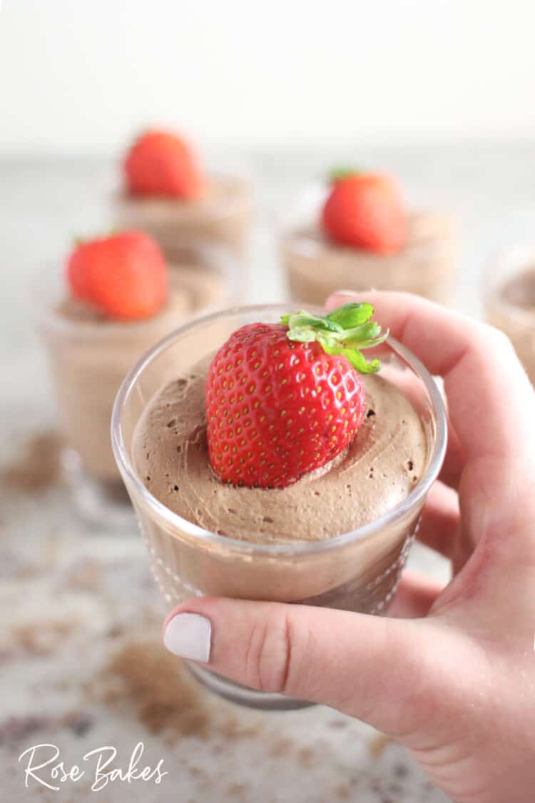 Creamy No-Bake Chocolate Cheesecake Cup Recipe in small clear glass held in hand topped with strawberry