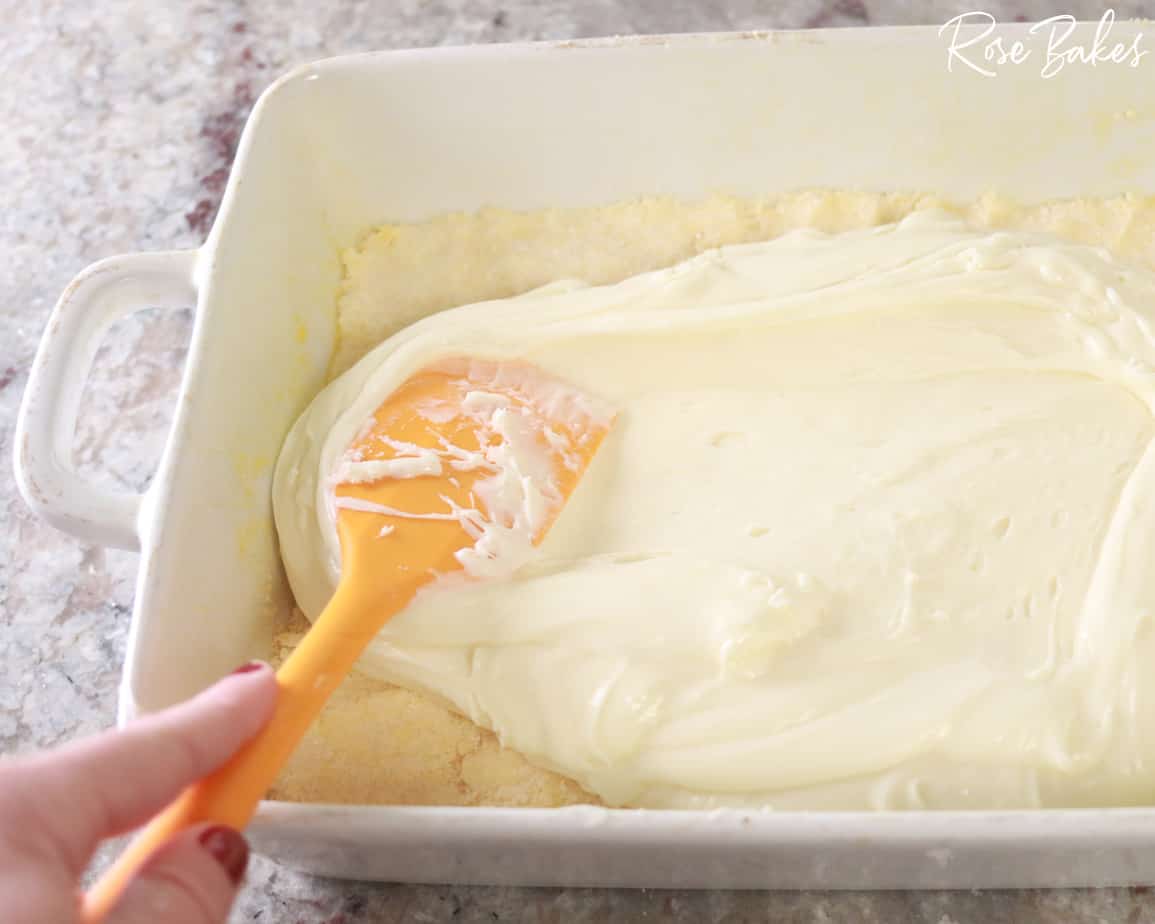 Cream cheese icing mixture being spread on top of crust 