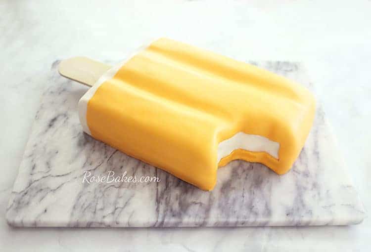 orange creamsicle cake or dreamsicle cake on a marble slab with bite missing
