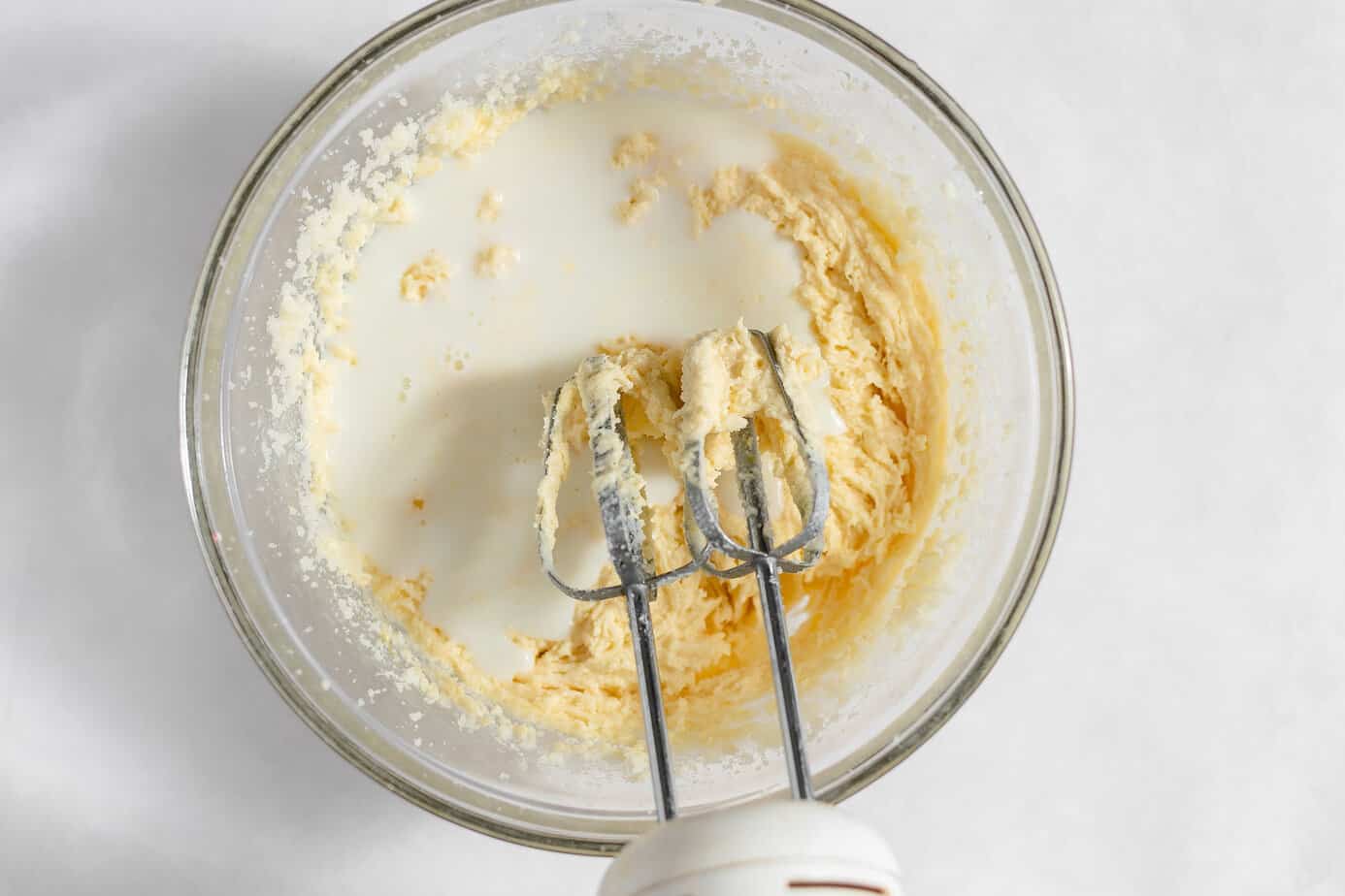 Milk added to the batter in a glass mixing bowl.