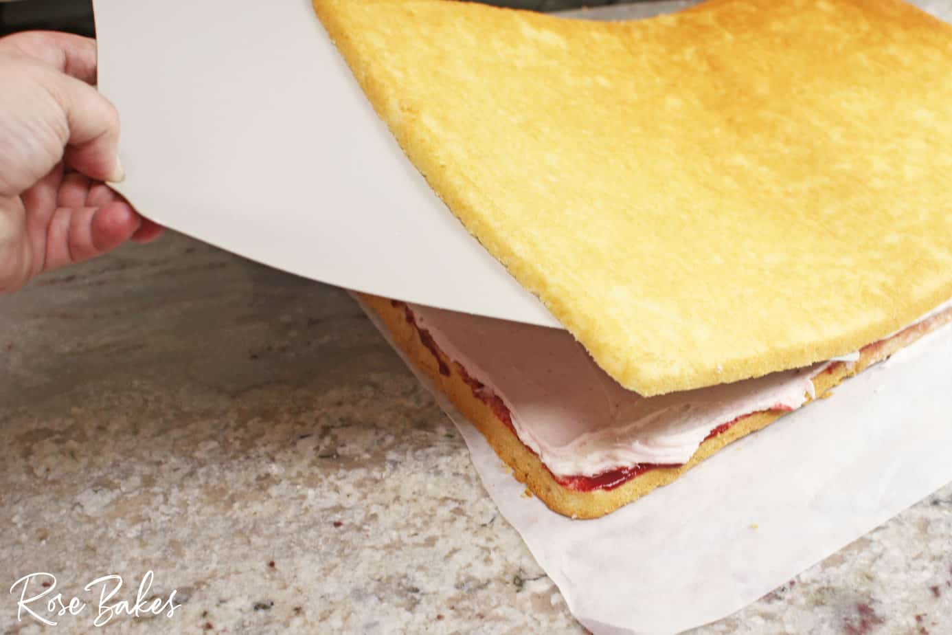 using a flexible cutting board to move the top layer back on top of the layer with filling and frosting.