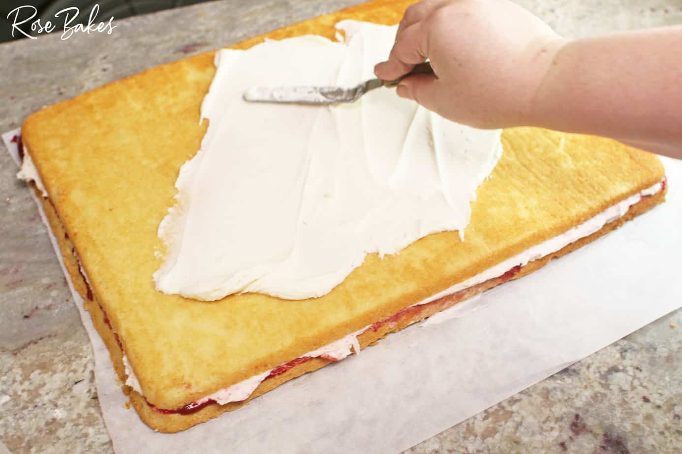 Frosting being added to the top cake layer