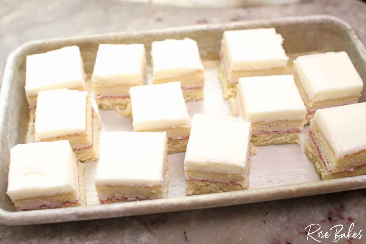 a dozen petit fours on a small baking sheet headed to the freezer
