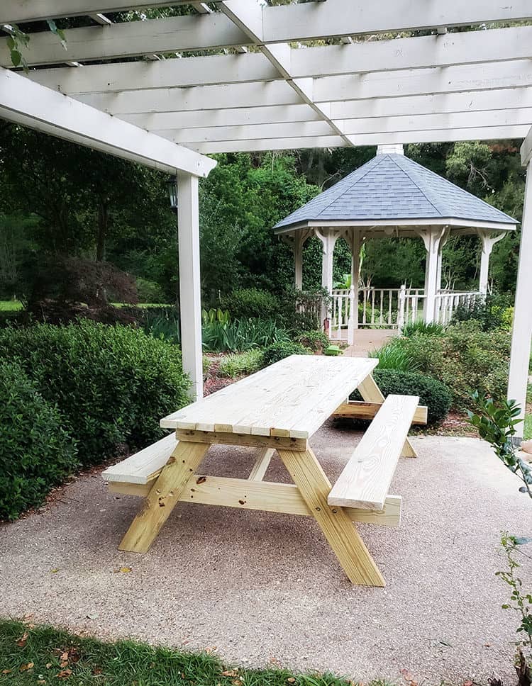 homemade 8 foot picnic table underneath arbor in backyard