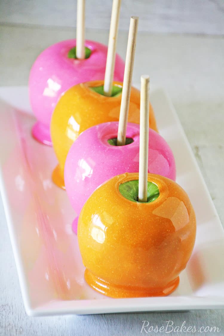 orange and pink candy apples on a white platter
