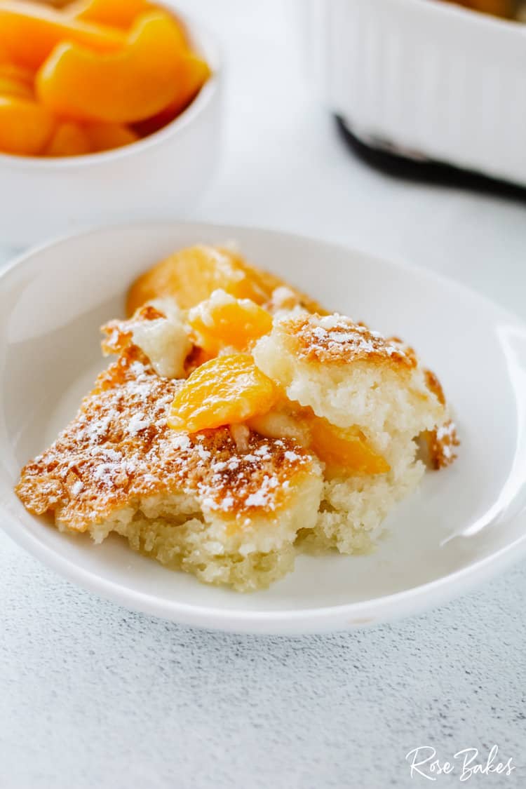 Easy Peach Cobbler on a white dish with powdered sugar sprinkled on top