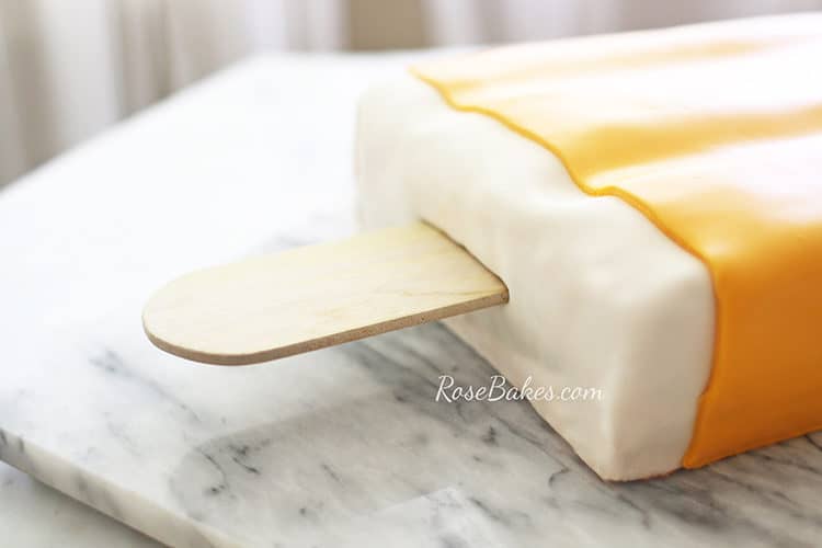 orange creamsicle cake or dreamsicle cake on a marble slab with lauan popsicle stick