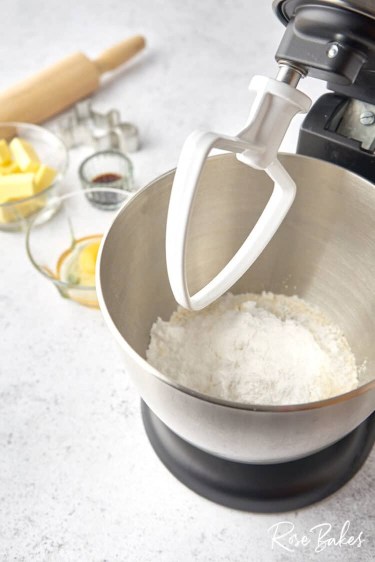 A stand mixer with flour and powdered sugar in the bowl.