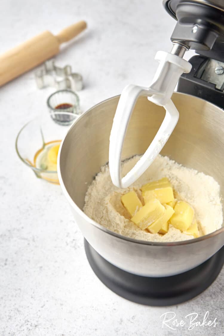 a stand mixer with cubed butter added to the flour and sugar.