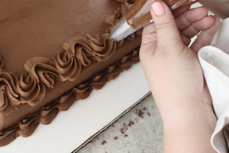 Piping on chocolate cake for Cake Decorating for Beginners Book