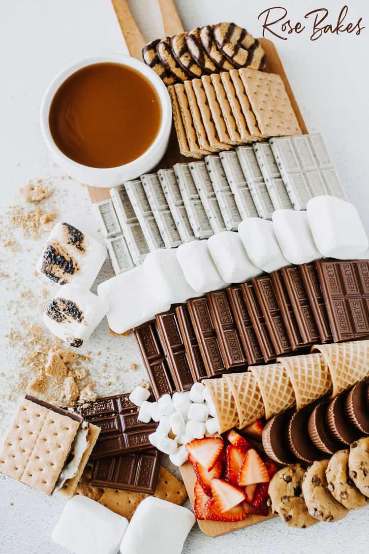 S'mores Charcuterie Board - a Campfire S'mores Board or S'mores Dessert Board filled with  marshmallows, chocolate bars, graham crackers, cookies strawberries and caramel sauce