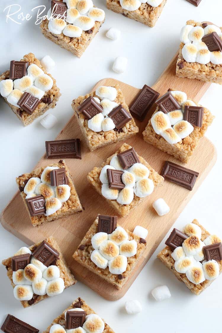 smores rice krispie treats cut into squares and sitting on a wooden cutting board and white counter