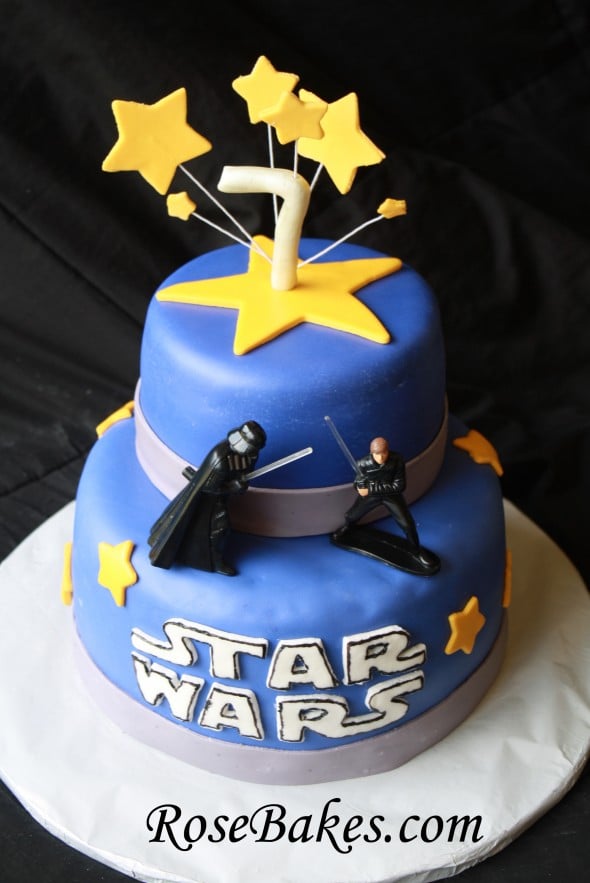 2 tiered blue fondant cake with Star Wars on the front with figurines.