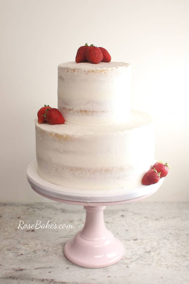 naked wedding cake with strawberries on a pink cake stand